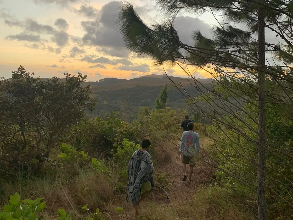 Two people walk along a mountain trail at sunset